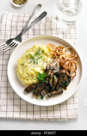 Tranches de foie de boeuf avec purée de pommes de terre et d'oignon frit sur plaque blanche. Foie (abats) Morceaux de boeuf aux légumes cuits. Banque D'Images