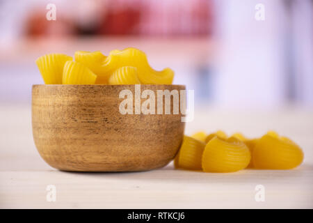 Lot de pâtes crues pipe rigate variété avec bol en bois dans la cuisine blanche Banque D'Images