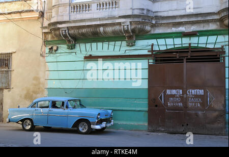 Scène de rue dans la Vieille Havane, Cuba, montrant un classique bleu voiture garée en face d'un bâtiment d'une porte métallique coulissante couvrant une entrée voûtée. Banque D'Images