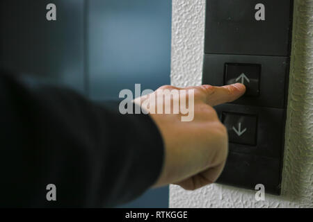 Une vue arrière d'un homme poussant un bouton d'ascenseur avec son index Banque D'Images