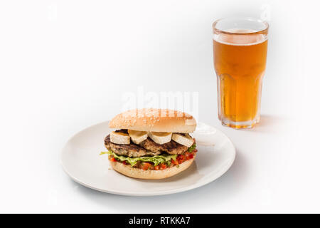 Cheeseburger sur une plaque avec patty de boeuf et de concombres, en tranches, avec un verre sur un fond isolé Banque D'Images