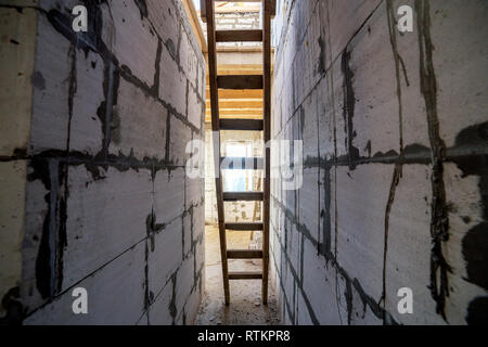 Intérieur maison en construction et rénovation. Vue en perspective de l'échelle en bois, futur escalier dans long couloir passage avec l'économie d'énergie wall Banque D'Images