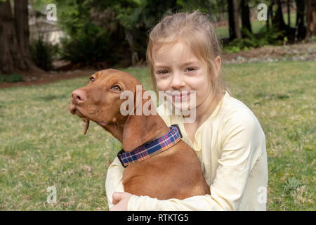 Issaquah, Washington, USA. Six ans, fille, serrant ses cinq mois Vizsla devint puppy 'Pepper'. Banque D'Images