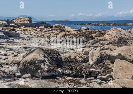 Détail d'un angle faible rocky Gabriola Island plage à marée basse, avec le détroit de Géorgie et phare de l'île d'entrée dans la distance (été 24). Banque D'Images