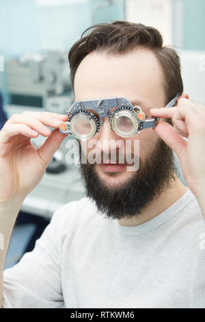Jeune homme avec montures d'essai clinique en ophtalmologie Banque D'Images