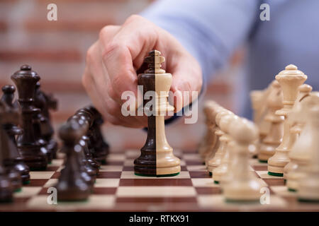 Close-up of Person's Hand le déplacement d'une pièce d'Échecs roi sur Chess Board Banque D'Images