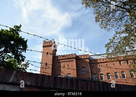 Vieux bâtiment en brique derrière mur avec des barbelés. Banque D'Images