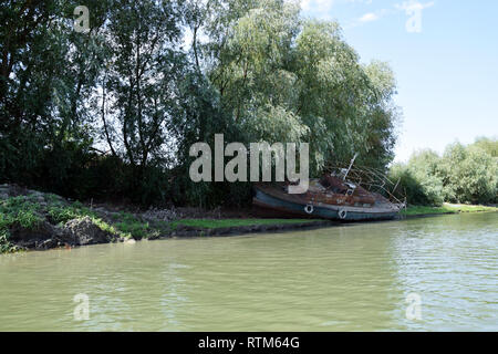 Bateau de pêche et vieux navire de pêche abandonnés sur la rive du fleuve. Le Delta du Danube, en Roumanie. Banque D'Images