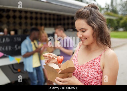 Femme heureuse avec wok et amis de camion alimentaire Banque D'Images