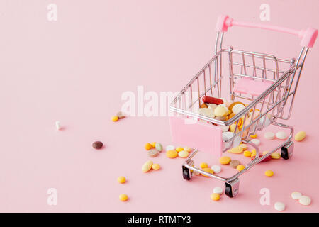 Panier du supermarché plein de pilules et drogues sur un fond rose. Les achats de médicaments, l'achat sur Internet. Télévision Banque D'Images