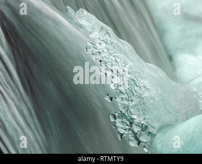 Fragment de la cascade en hiver. L'eau gelée des éclaboussures sur l'arrière-plan de jets d'eau colorés Banque D'Images