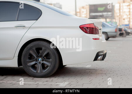 Kiev, UKRAINE - 27 Février 2019 : side view of white voiture garée en stationnement pavé sur zone banlieue floue sur fond routier journée ensoleillée. Trans Banque D'Images