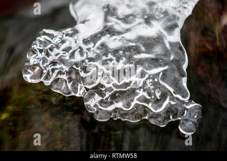 Fragment de la cascade en hiver. L'eau gelée des éclaboussures sur l'arrière-plan de jets d'eau colorés Banque D'Images