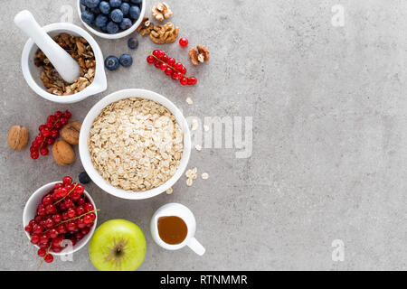 Avec les baies fraîches d'avoine à cuisson, de bleuet, de groseille rouge, de noix et de miel. Le petit-déjeuner végétarien sain concept alimentaire haut, vue, télévision lay Banque D'Images