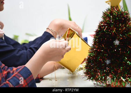 Deux femme s mains wrapping christmas gift, Close up, non préparé noël présente sur le tableau à l'intérieur de ciment accueil parc Banque D'Images