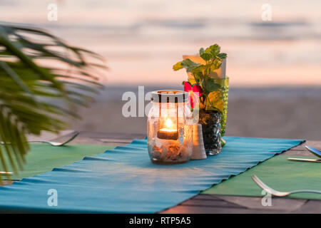 Bougie sur une table dans un restaurant avec vue sur le coucher du soleil sur l'île de Koh Chang, Thaïlande Banque D'Images