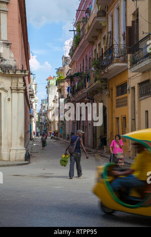 La Havane, Cuba - 06 janvier 2013 : une vue sur les rues de la ville avec des cubains. Un homme marche au milieu de la rue, un taxi à l'avant-plan Banque D'Images