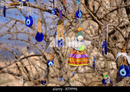 Arbre généalogique Public décoré de mauvais Œil et pendentifs poupée sur un côté de la route de la Cappadoce. Arrière-plan flou de la formation de la roche locale Banque D'Images