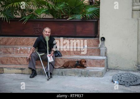 La Havane, Cuba - 21 janvier 2013 : une vue sur les rues de la ville avec des cubains. Un vieil homme est assis avec un chien, il vend des journaux. Banque D'Images