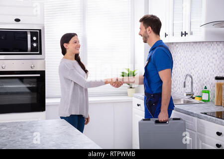 Vue latérale du jeune homme Plombier Shaking Hands With happy Woman Banque D'Images