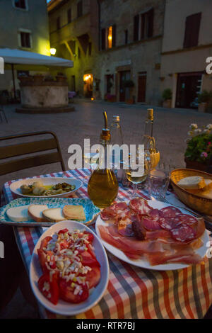 Vin blanc et de savoureux en-cas faits maison italienne. Table de dîner italien avec des antipasti, fromage et jambon, Pienza, Toscane, Italie Banque D'Images
