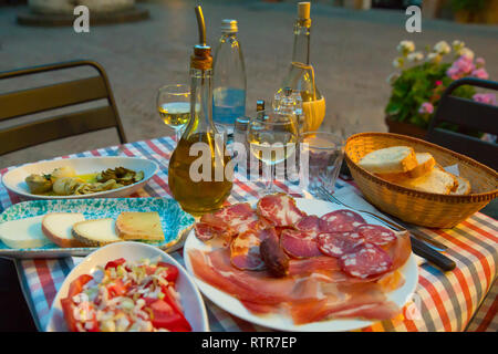 Vin blanc et de savoureux en-cas faits maison italienne. Table de dîner italien avec des antipasti, fromage et jambon, Pienza, Toscane, Italie Banque D'Images
