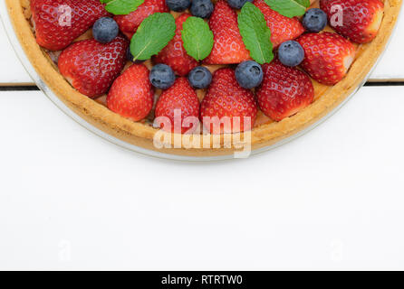 Tarte maison avec des fraises et des bleuets sur fond de tableaux blancs. Banque D'Images