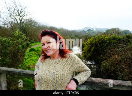 Young woman smiling at camera, debout sur un pont - John Gollop Banque D'Images