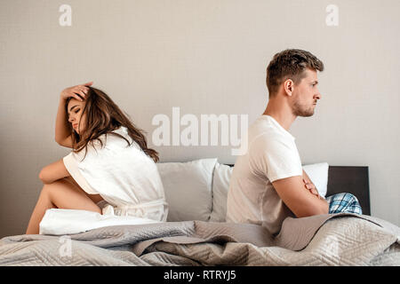 Jeune couple dans la chambre à coucher. Malheureux l'homme et la femme sont assis dos à dos dans le lit, querelle de couple accueil scène, pause dans les relations Banque D'Images