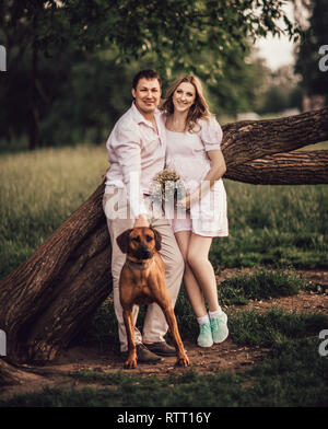 Jeune famille avec leur chien près d'un grand arbre. Banque D'Images