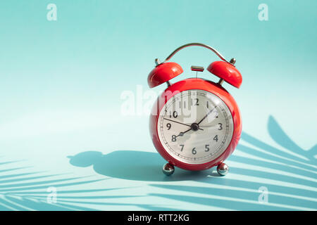 Les concepts de l'heure d'été idée avec réveil et feuilles tropicales ombre sur fond coloré.Maison de vacances images décoration Banque D'Images