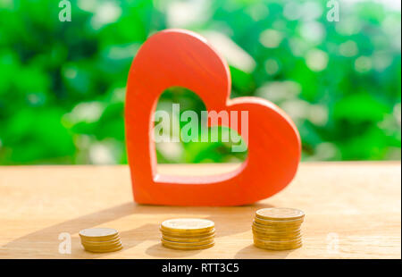 Coeur en bois rouge et argent. Le concept de l'épargne et l'accumulation de l'argent. Organisme de bienfaisance du domaine de la santé. Don. Les achats de la Saint-Valentin. Soft f sélective Banque D'Images