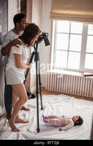 Mère et père de prendre des photos d'une petite fille qui sont couchées sur le sol, première session de photo, temps libre, temps libre, copie, espace photo pleine longueur Banque D'Images