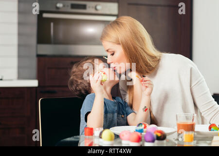 Happy blonde mère et son fils de quatre ans faire des oeufs de Pâques, bénéficiant de temps libre passé ensemble à la maison. Célébrer Pâques en famille. Parent Banque D'Images