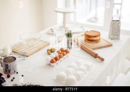 Table de cuisine avec des outils et ingrédients pour faire un dessert, la photo en gros chambre cuisine vide. Banque D'Images