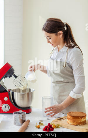 Jolie jeune fille de verser le lait dans la crème, Close up side view photo Banque D'Images