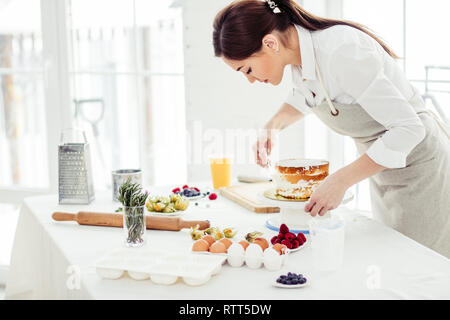 Chef Créatif à l'aide d'un banc de la décapeuse à lisser les couches de crème au beurre. close up side view photo, copy space Banque D'Images
