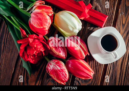 Boîte-cadeau avec café et bouquet de tulipes fraîches sur fond de bois. Matin surprise. Bonjour. Banque D'Images