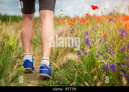 Jeune homme d'exécution sur champ de coquelicots en été. Le sport. Mode de vie sain Banque D'Images