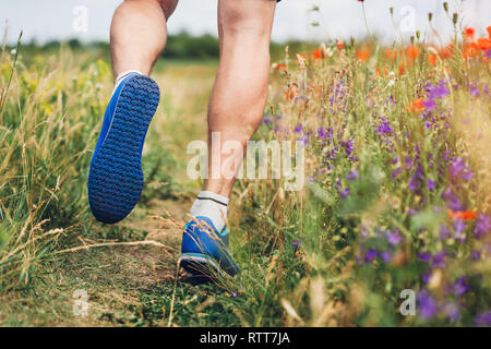 Jeune homme d'exécution sur champ de coquelicots en été. Le sport. Mode de vie sain Banque D'Images