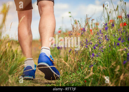 Jeune homme d'exécution sur champ de coquelicots en été. Le sport. Mode de vie sain Banque D'Images