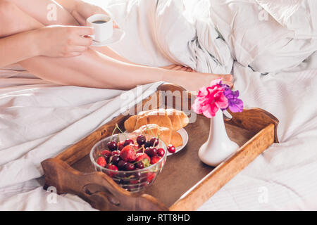 Femme ayant le café et croissants aux fruits rouges au lit Banque D'Images