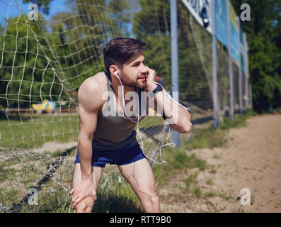 Un sportif barbu est par la moustiquaire dans le parc Banque D'Images