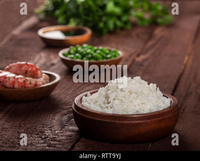 Riz blanc cuit dans bol en bois aux crevettes, pois de bois sur un fond brun. Banque D'Images