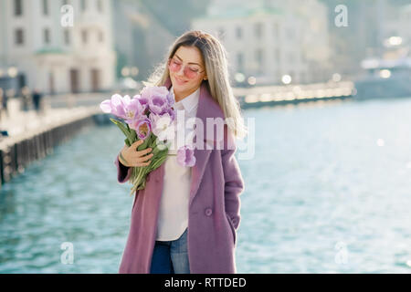 Belle femme heureuse avec les cheveux droits tenant un bouquet de tulipes roses d'une journée ensoleillée. Banque D'Images