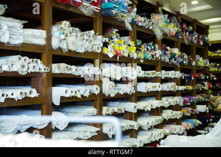 Avis de rouleaux de tissu de différentes couleurs et de motifs sur des étagères en tissu boutique Banque D'Images