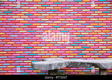 Mur de briques de couleur et texture de fond avec banc en bois. Banque D'Images