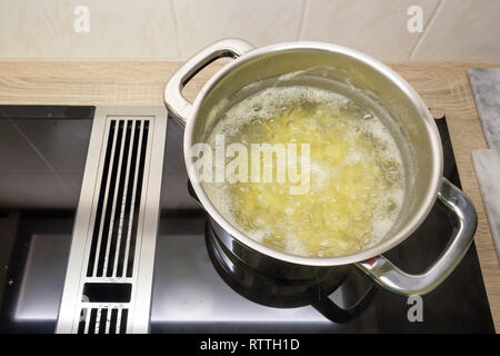 Les pommes de terre dans l'eau bouillante dans une casserole sur une cuisinière à induction Banque D'Images