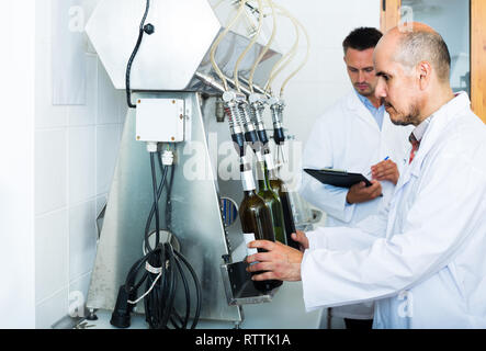 Portrait of mature européenne homme winery travailleur avec des machines d'embouteillage sur factory Banque D'Images