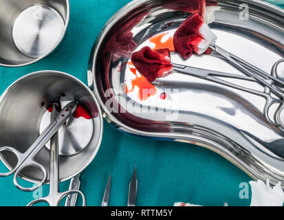 Chirurgie ciseaux avec torundas imbibé de sang sur un plateau métal dans une salle d'opération, la composition horizontale, conceptual image Banque D'Images